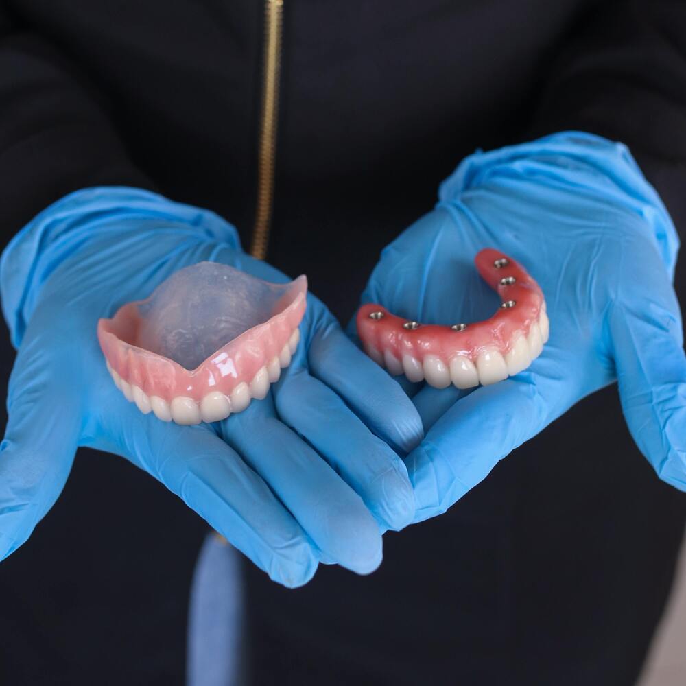 A dental professional holding dentures