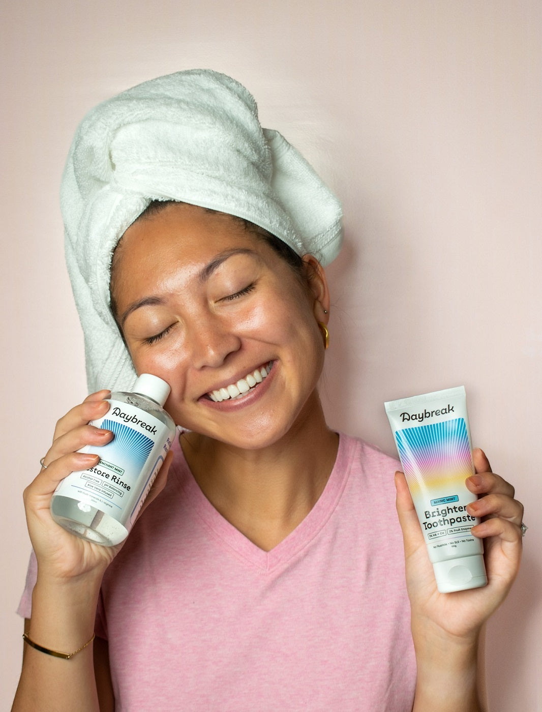 A woman with a healthy smile holds the Daybreak toothpaste and mouthwash lovingly